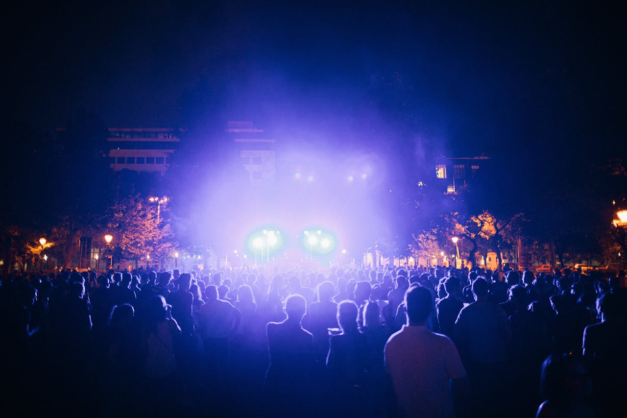 A lively outdoor concert scene at night with colorful lights and a large audience.